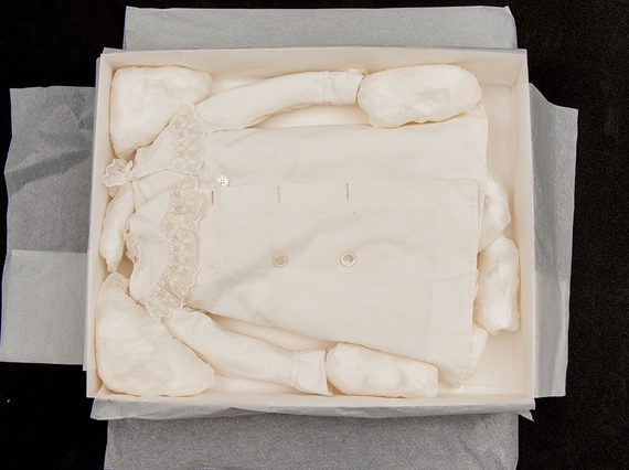 A small white blouse packed in a cardboard box with tissue puffs.